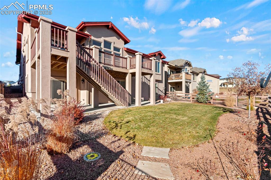 Back of property with stucco siding, a patio, stairway, and a wooden deck