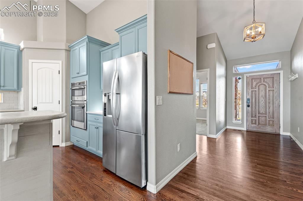 Entrance foyer with dark wood finished floors, a chandelier, and high vaulted ceiling