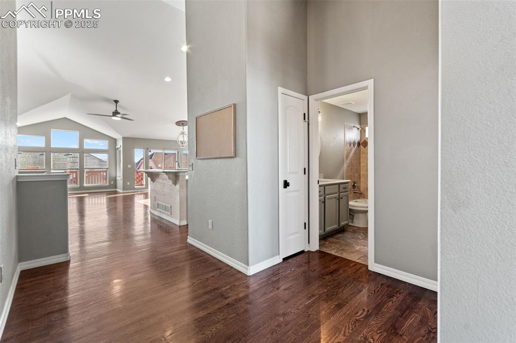 Hall with dark wood-style flooring, high vaulted ceiling, and a textured wall