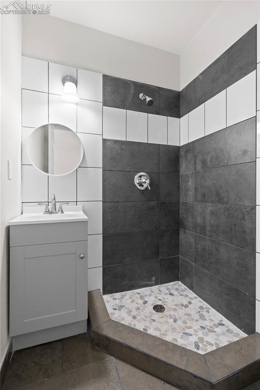 Bathroom featuring tiled shower, vanity, and tile patterned floors