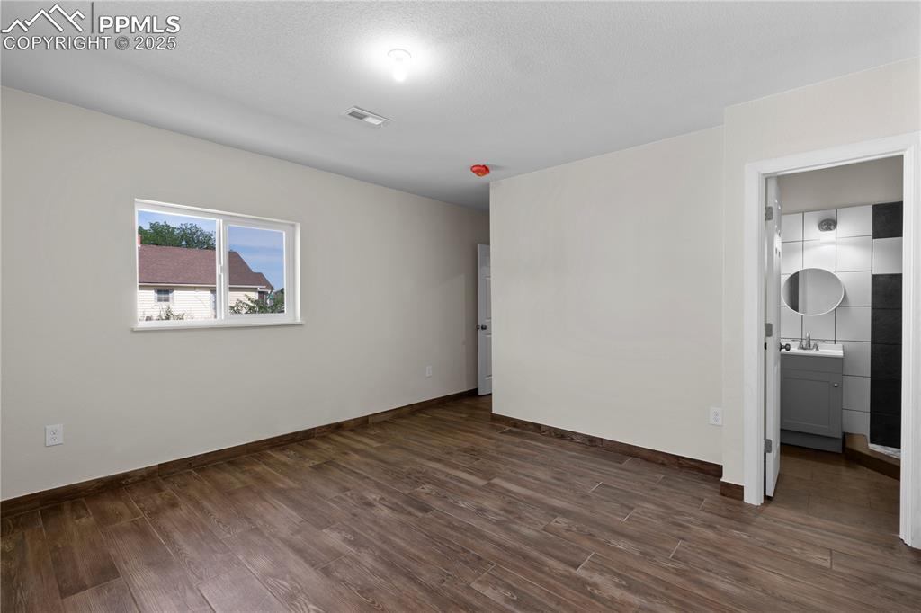 Unfurnished bedroom featuring a sink and dark wood-style flooring
