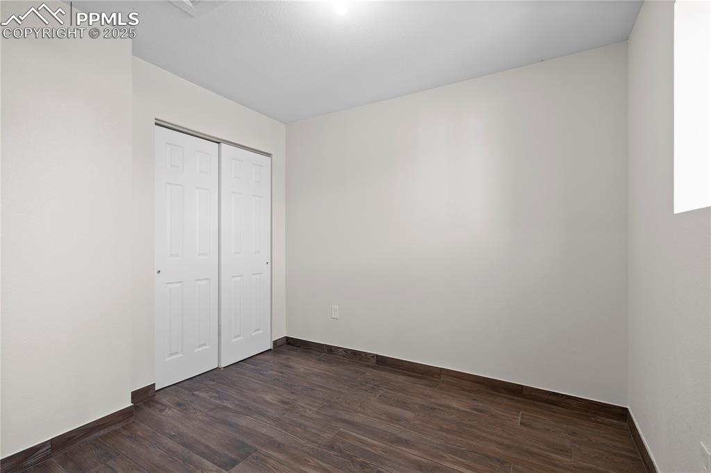 Unfurnished bedroom featuring dark wood-style floors and a closet