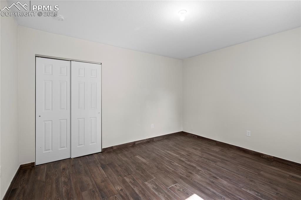 Unfurnished bedroom featuring dark wood finished floors and a closet
