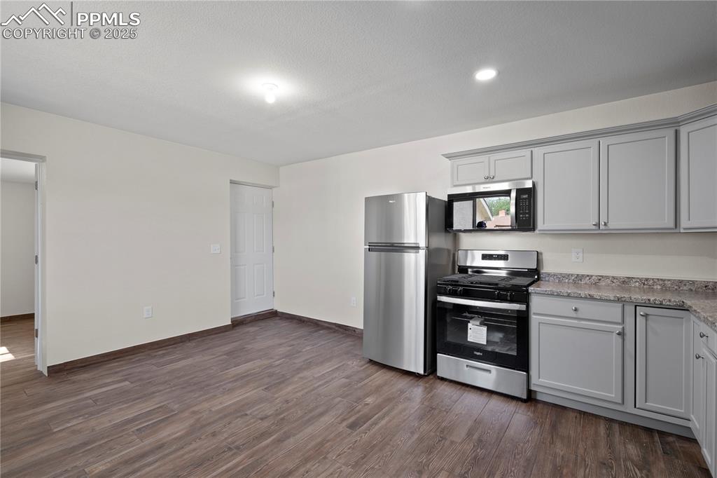 Kitchen with appliances with stainless steel finishes, dark wood finished floors, light countertops, and gray cabinets