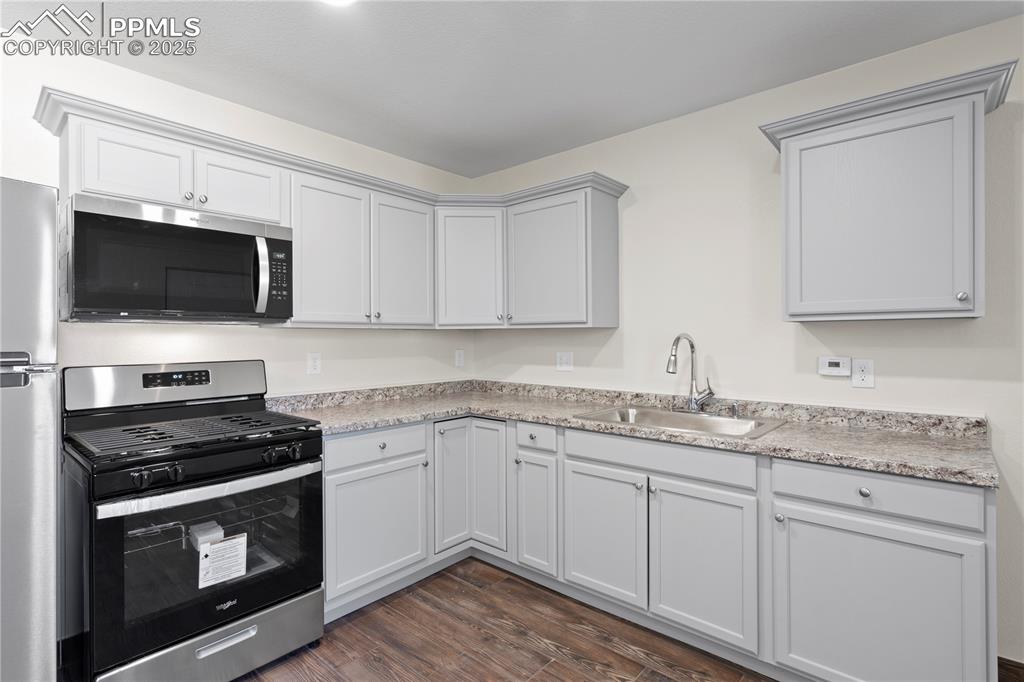 Kitchen featuring appliances with stainless steel finishes, light countertops, and dark wood-style floors
