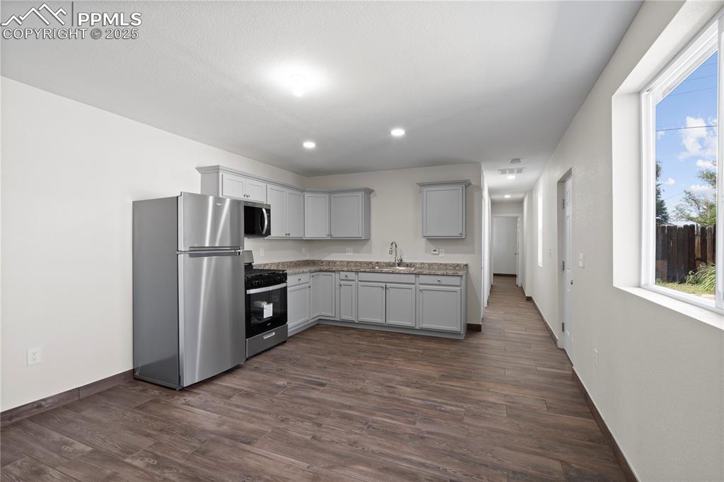 Kitchen featuring appliances with stainless steel finishes, dark wood-style floors, gray cabinetry, and recessed lighting