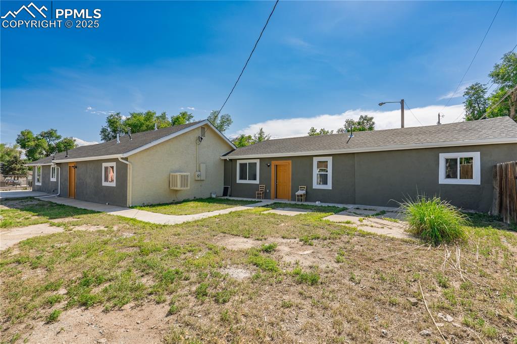 View of front of property with stucco siding and a wall unit AC