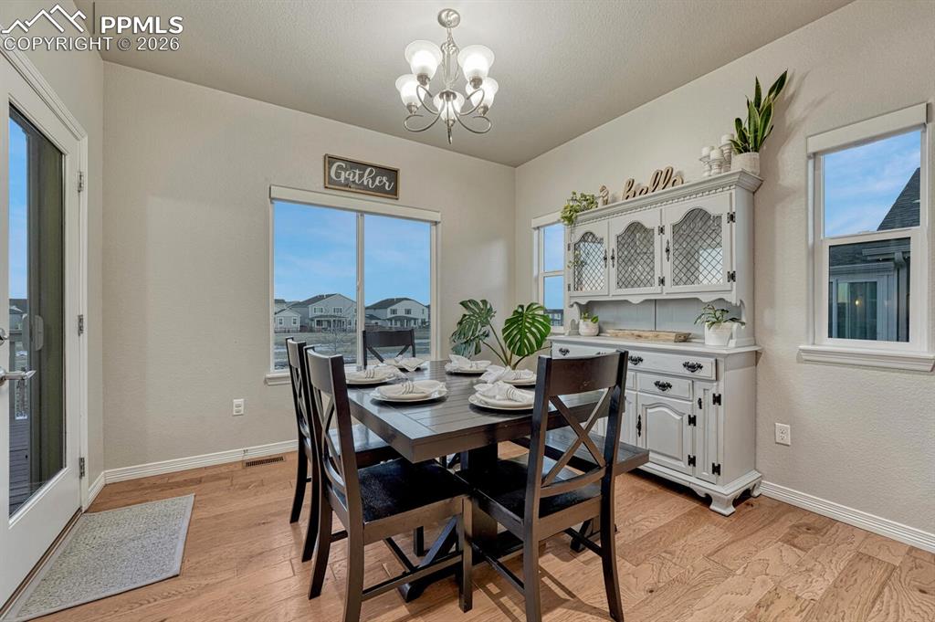 Dining room with a chandelier, healthy amount of natural light, and light wood-style flooring