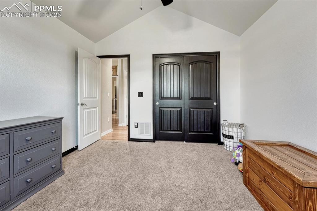 Bedroom featuring light carpet, lofted ceiling, ceiling fan, and a closet