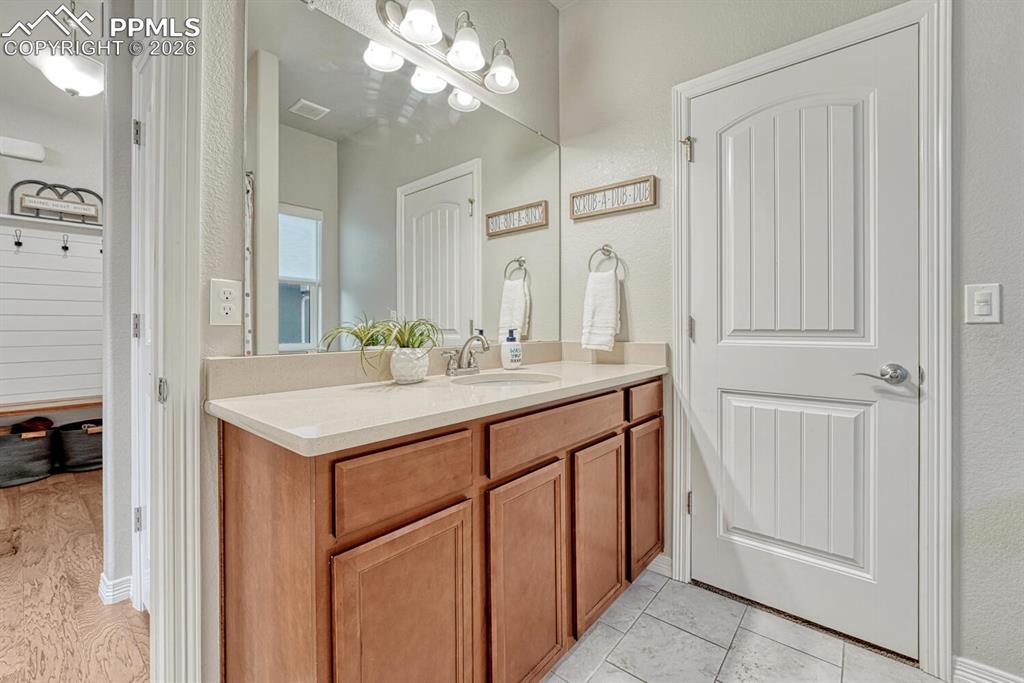 Bathroom featuring vanity, a textured wall, and light tile patterned floors