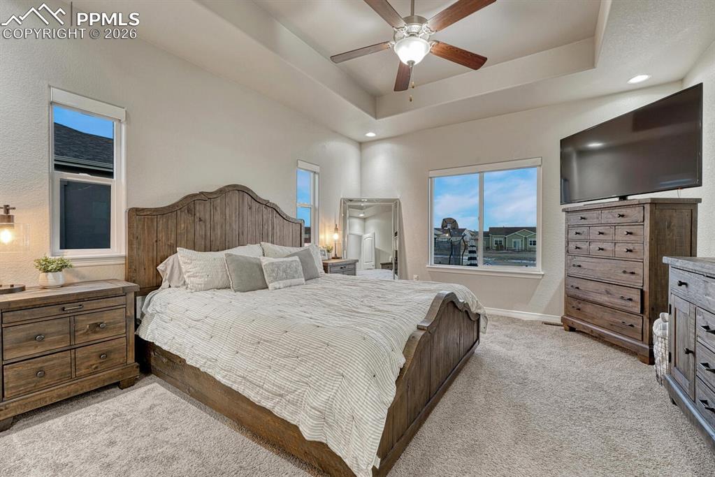 Bedroom featuring a tray ceiling, light carpet, ceiling fan, and recessed lighting