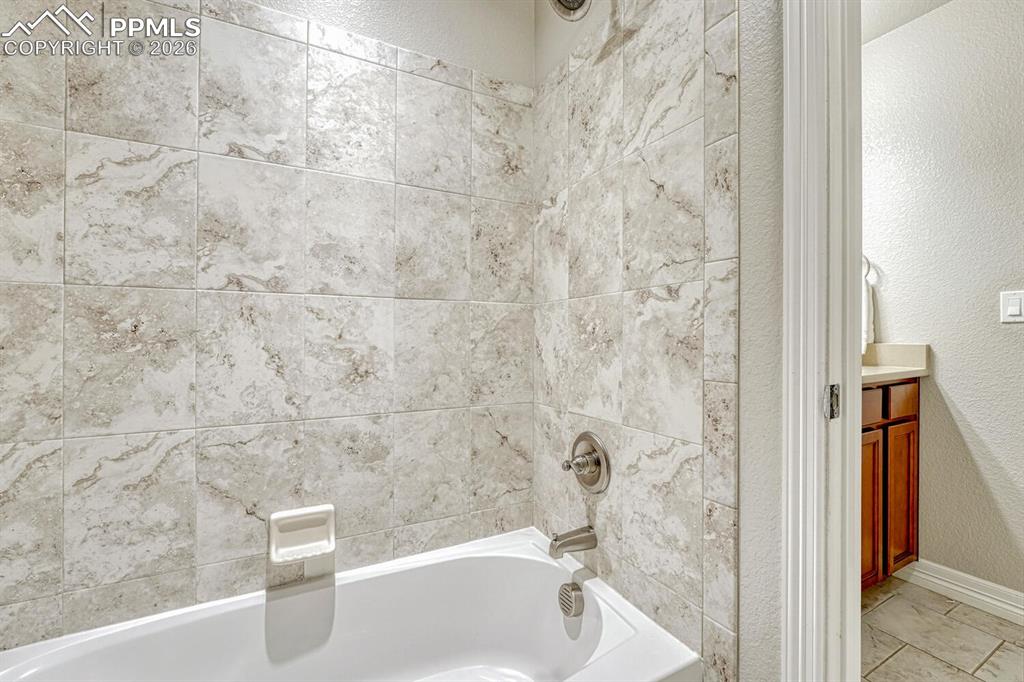 Full bathroom featuring a textured wall, bathing tub / shower combination, and vanity