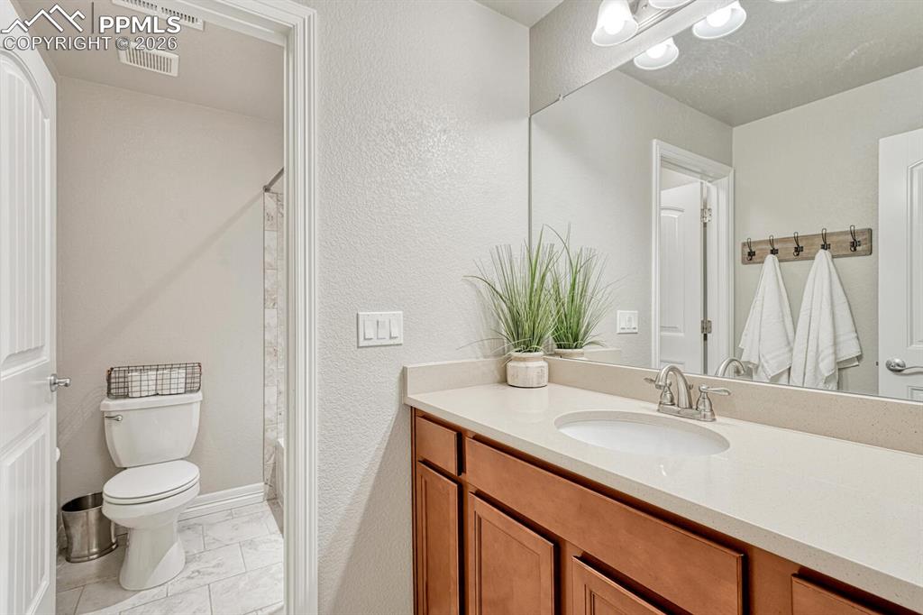 Full bathroom featuring vanity, light marble finish floors, a shower with curtain, and a textured wall