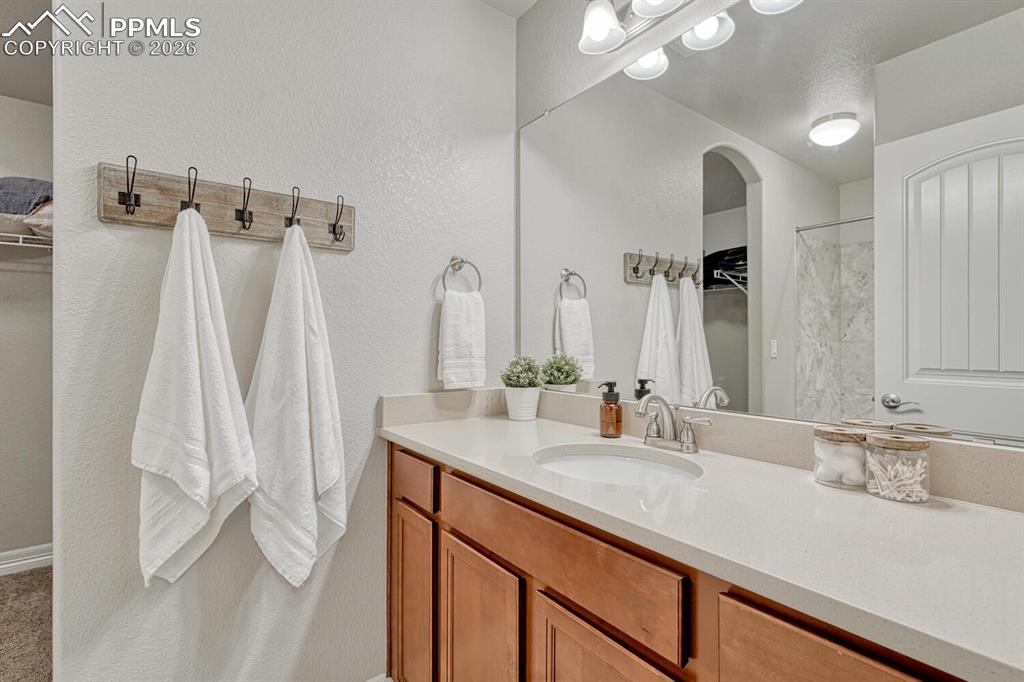Bathroom featuring vanity, a spacious closet, a shower with shower curtain, and a textured wall