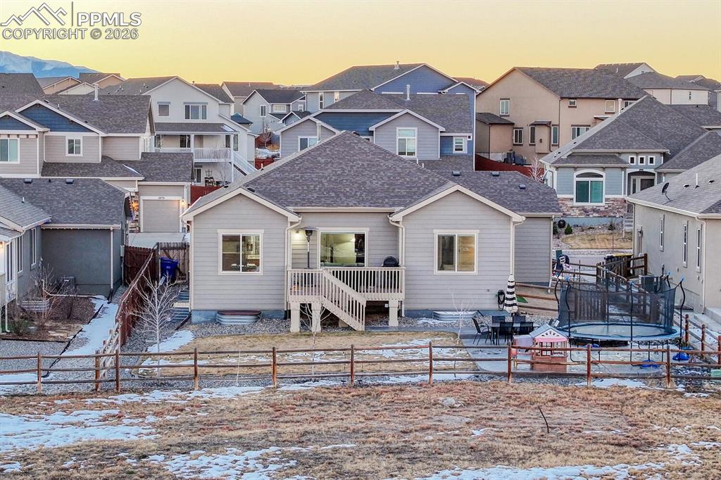 Rear view of property featuring a patio area, a fenced backyard, a trampoline, a residential view, and a deck