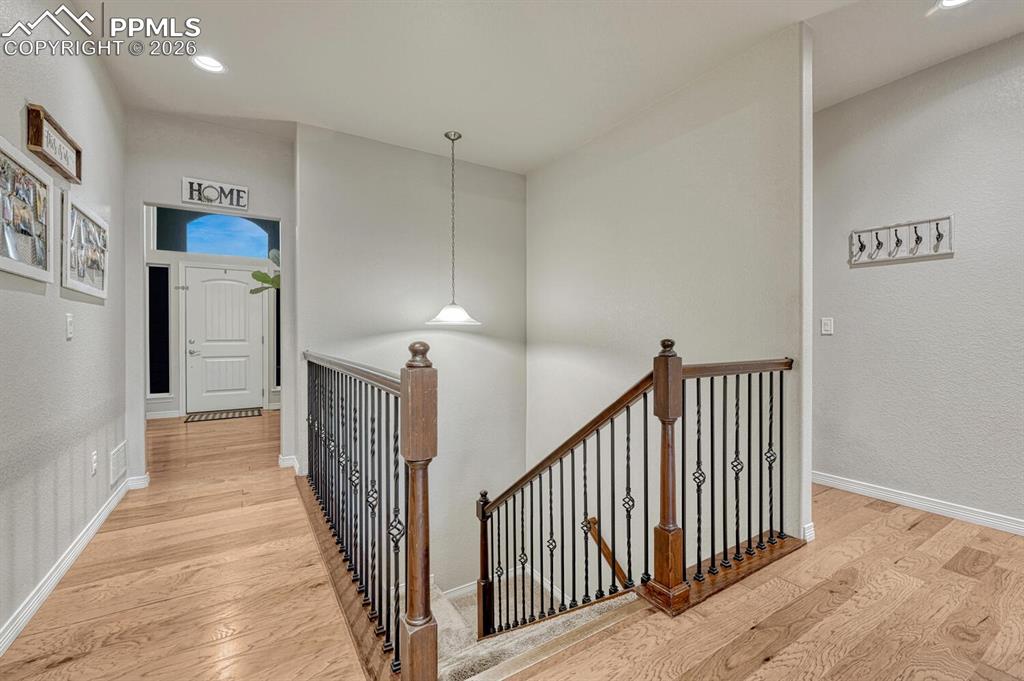 Hallway with an upstairs landing, light wood-style flooring, recessed lighting, and a textured wall