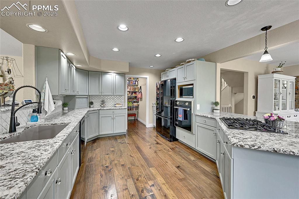 Kitchen featuring gas range in peninsula, pendant lighting, black appliances, and large walk in pantry 