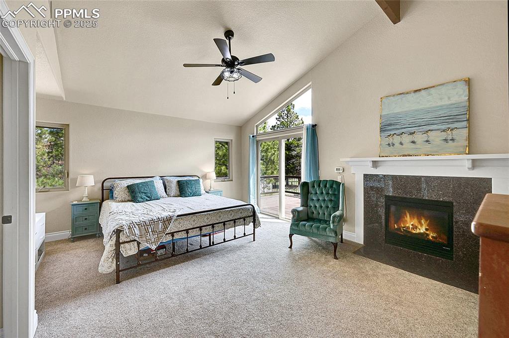 featuring a tiled fireplace, ceiling fan, vaulted ceiling, and walk out to private deck. 
