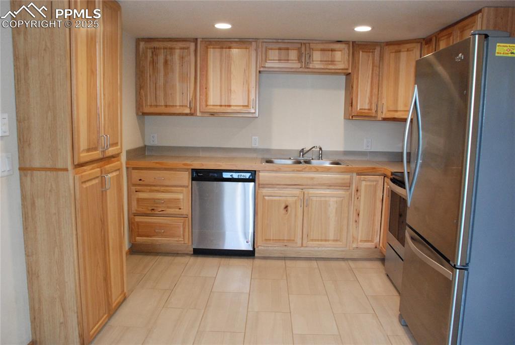 The kitchen features natural wood cabinets and ceramic tile flooring.