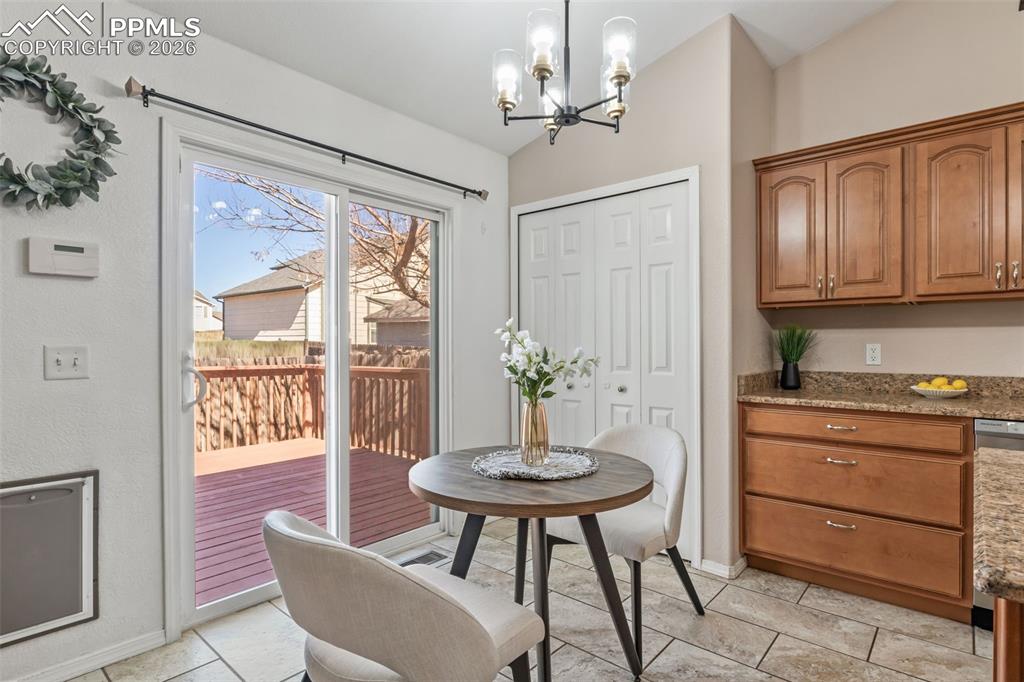 Dining area with suspended lighting, lofted ceiling, and light tile patterned floors