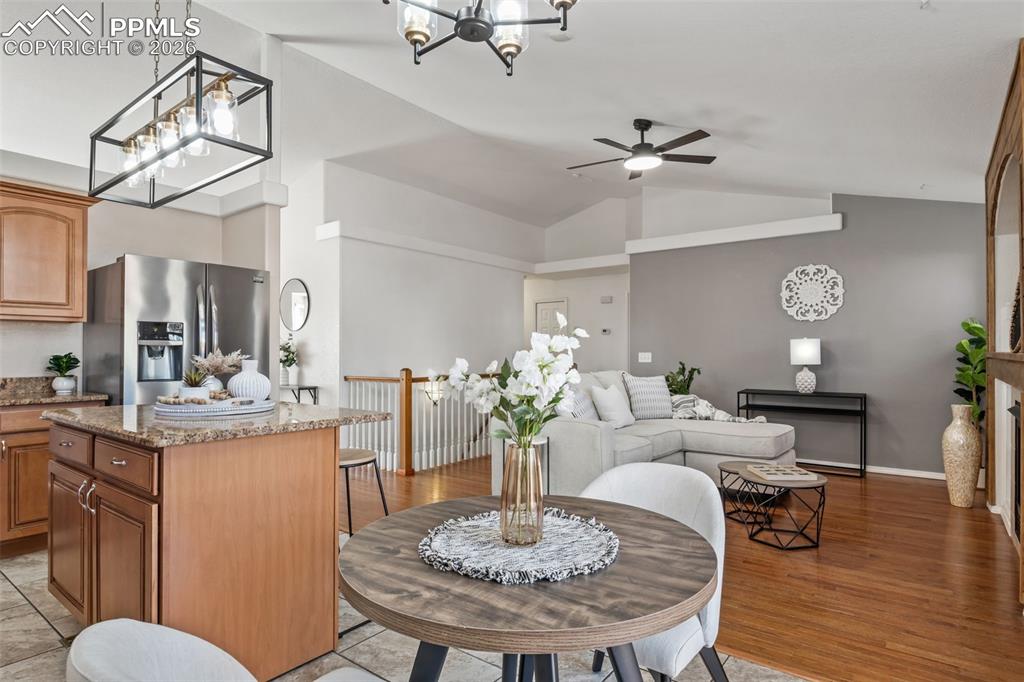 Dining room with lofted ceiling, a chandelier, a ceiling fan, and light wood-style flooring
