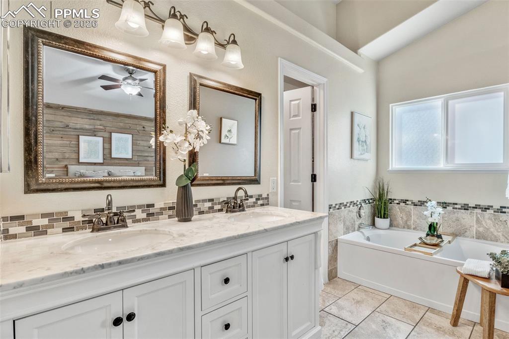 Full bathroom featuring a bath, double vanity, and a ceiling fan
