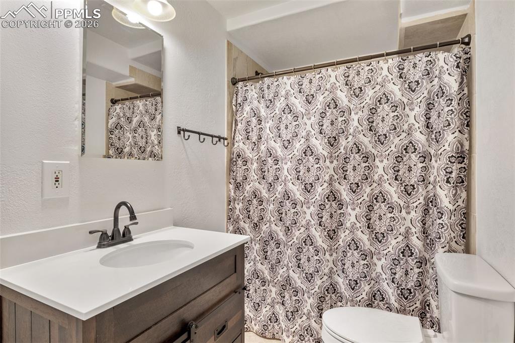 Full bath featuring a textured wall, vanity, and a shower with shower curtain