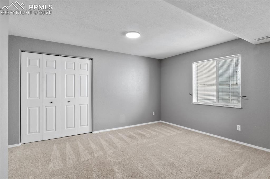 Unfurnished bedroom featuring light colored carpet, a closet, and a textured ceiling