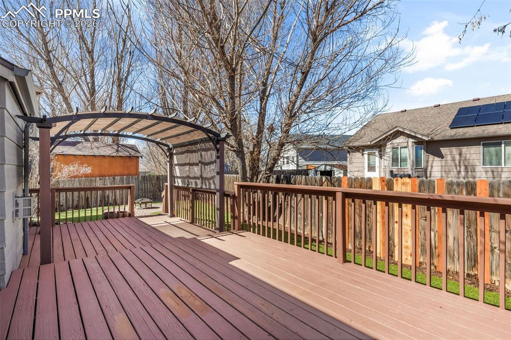 Wooden terrace with a fenced backyard