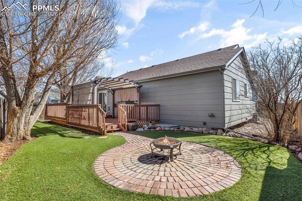 Rear view of house featuring an outdoor fire pit, a deck, and a shingled roof