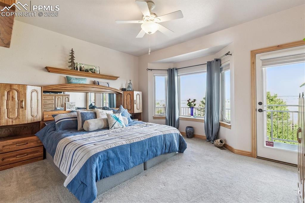 Carpeted bedroom with a ceiling fan and access to exterior deck
