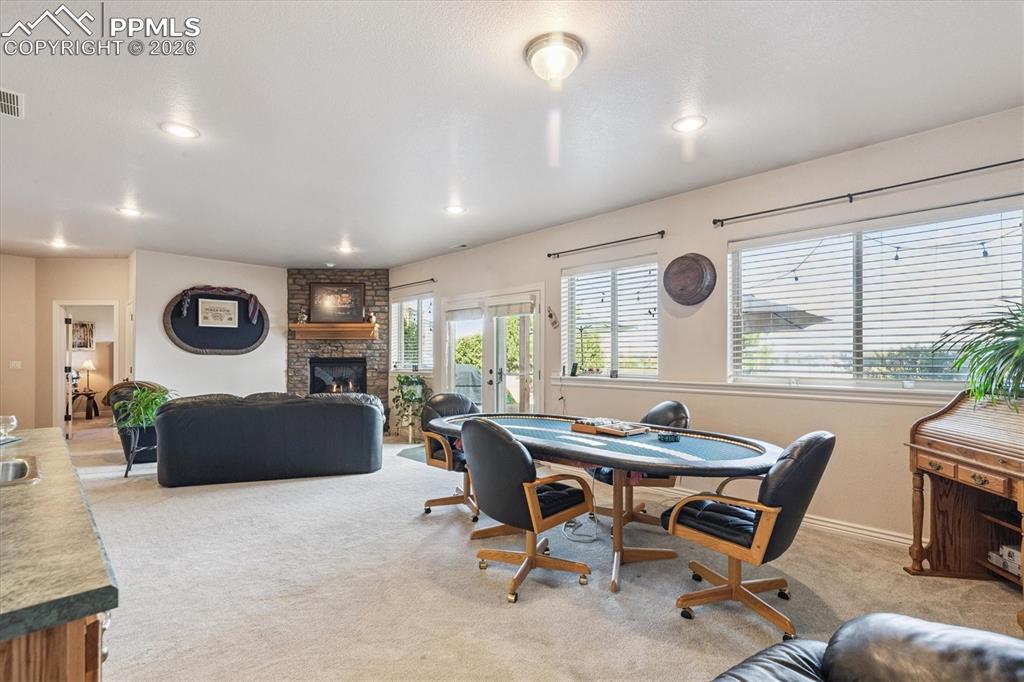 Dining area featuring a fireplace, light colored carpet, french doors, and recessed lighting