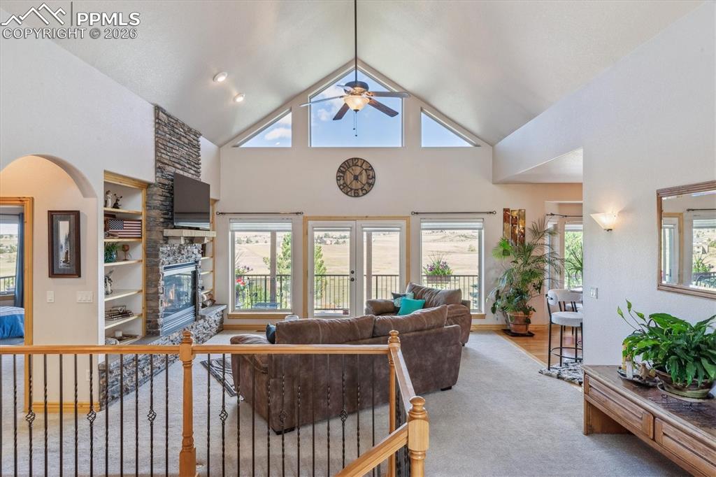 Living area featuring high vaulted ceiling, healthy amount of natural light, a fireplace, and built in shelves
