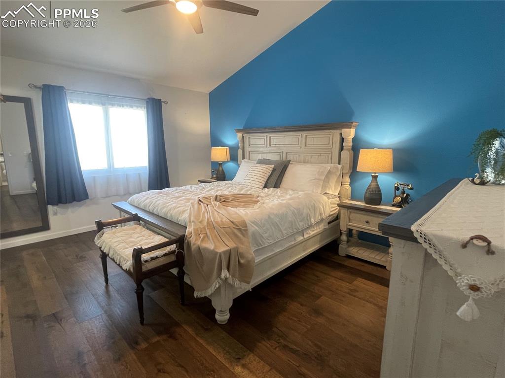 Bedroom featuring dark wood-style floors, vaulted ceiling, and a ceiling fan