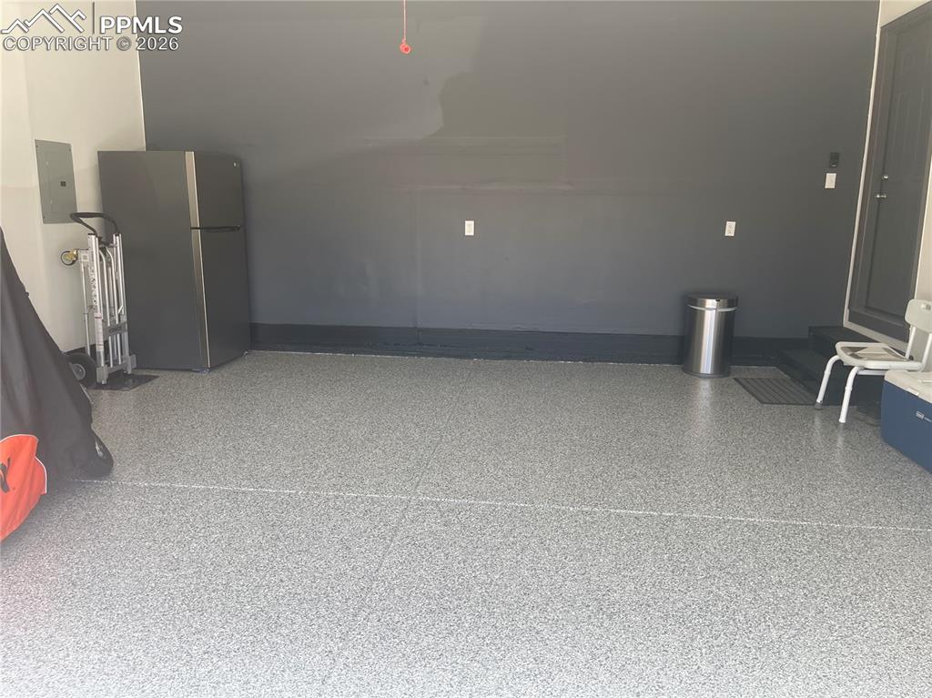 Garage with freestanding refrigerator and electric panel