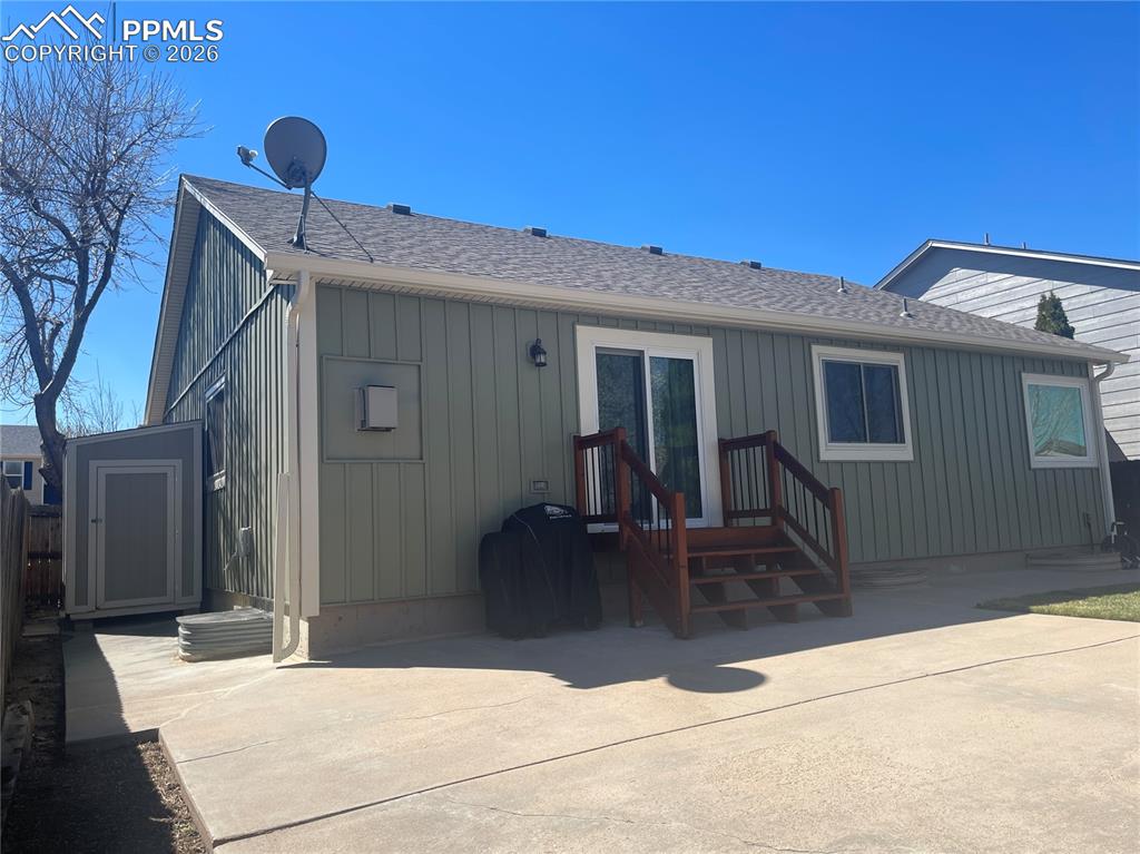 Rear view of property with roof with shingles, board and batten siding, and a patio
