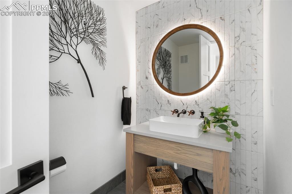 Main Level Powder Room with custom made back-lit mirror and custom wall mounted faucet.