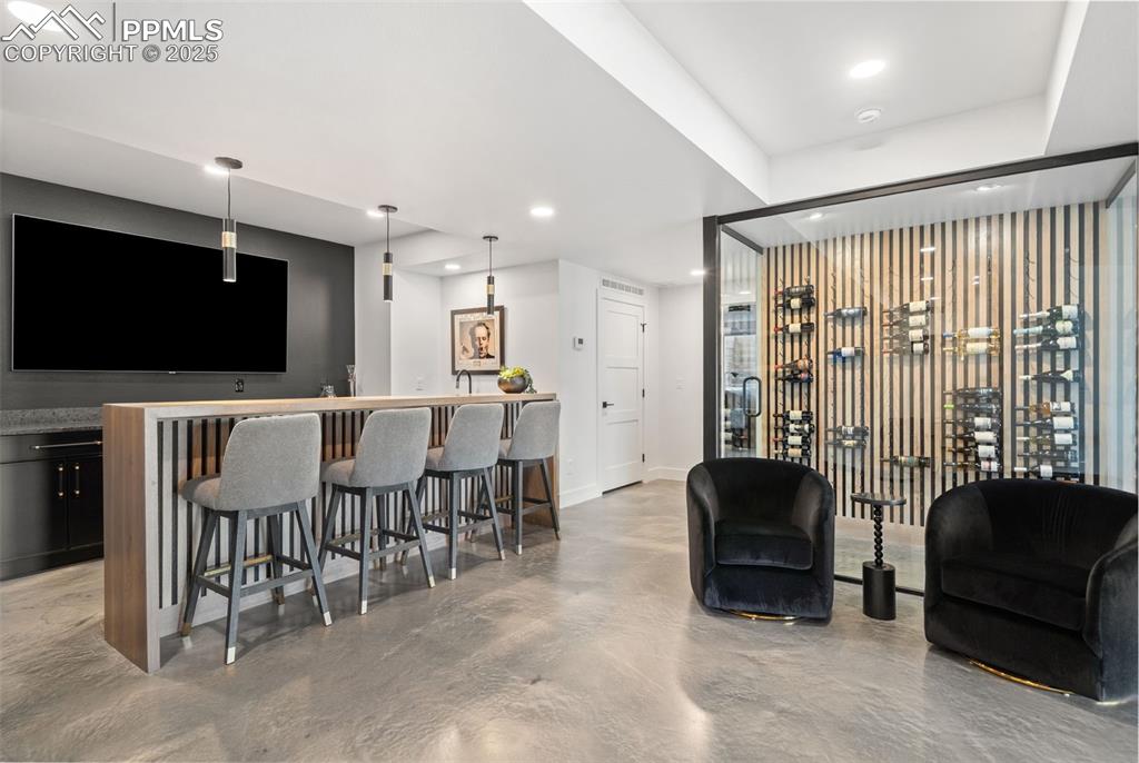 Adjacent to the glass encased wine cellar is the walk behind bar with tons of storage and an 85" TV!