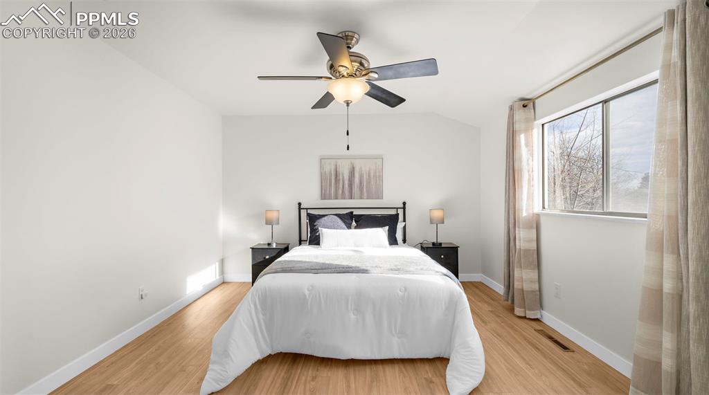 Bedroom with light wood-style flooring, ceiling fan, and vaulted ceiling