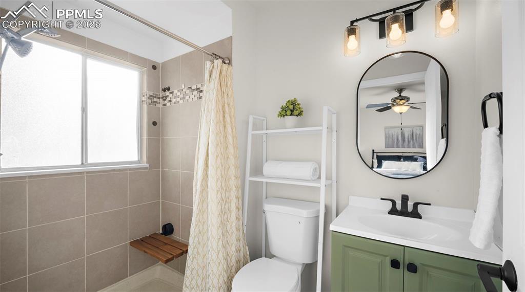 Full bathroom with vanity, a shower stall, and ceiling fan