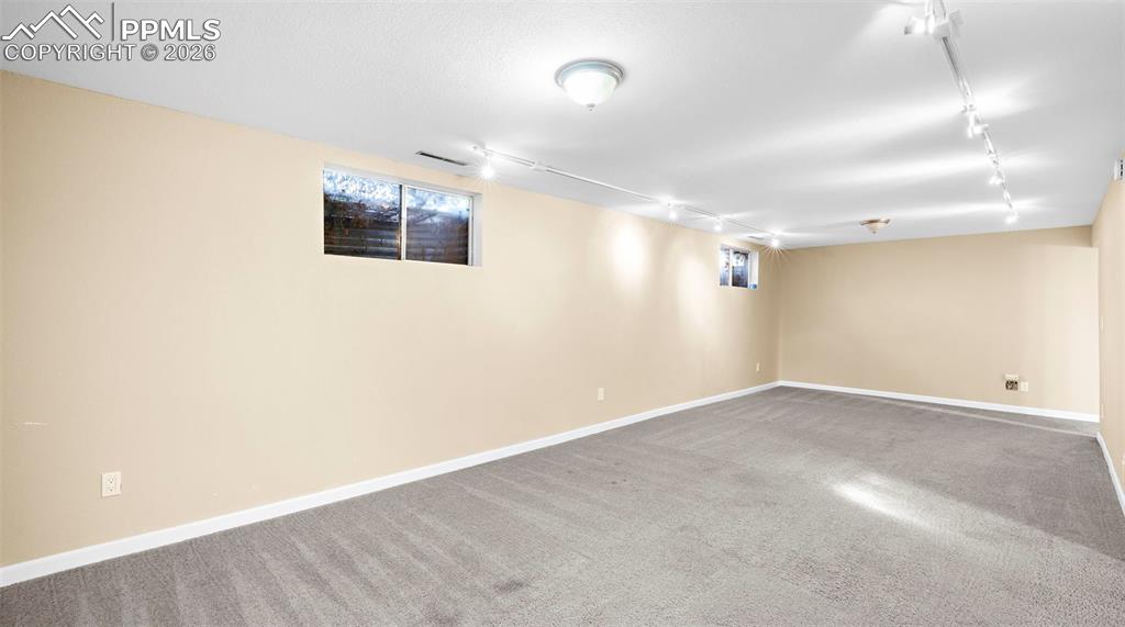 Basement with rail lighting and carpet floors