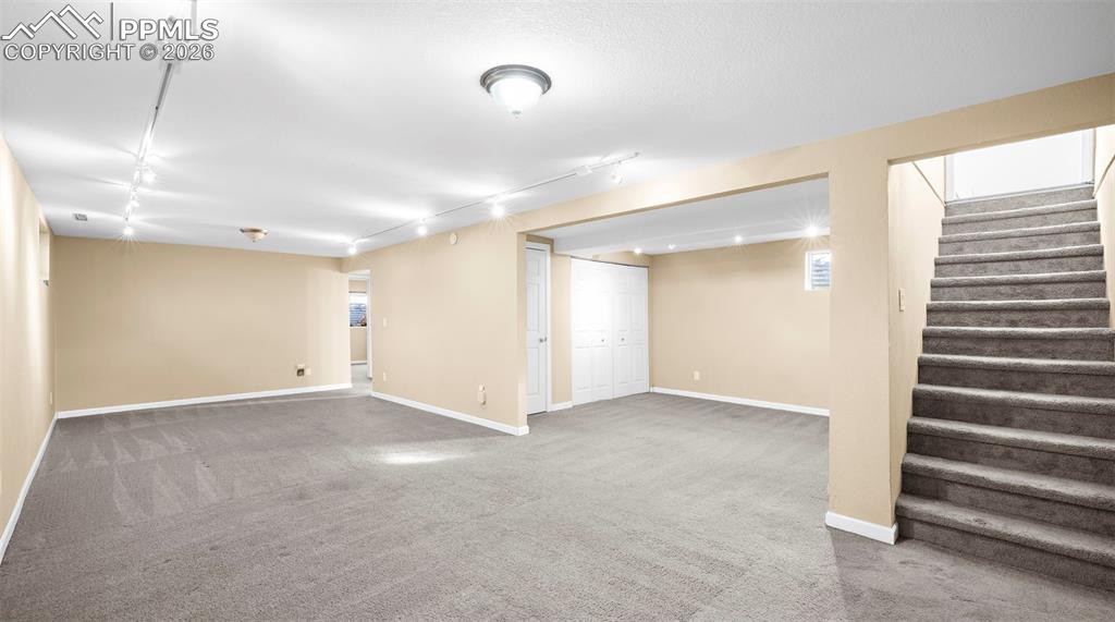 Finished basement featuring light colored carpet and track lighting