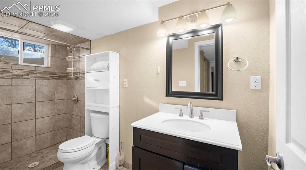 Full bathroom with vanity, a shower stall, and a textured wall