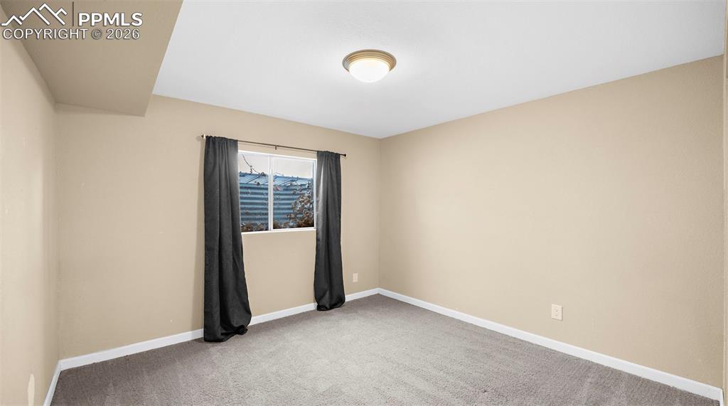 Spare room with baseboards and light carpet