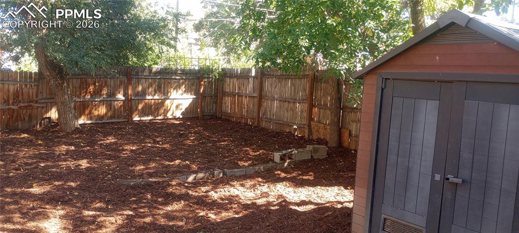 Fenced backyard with storage shed.
