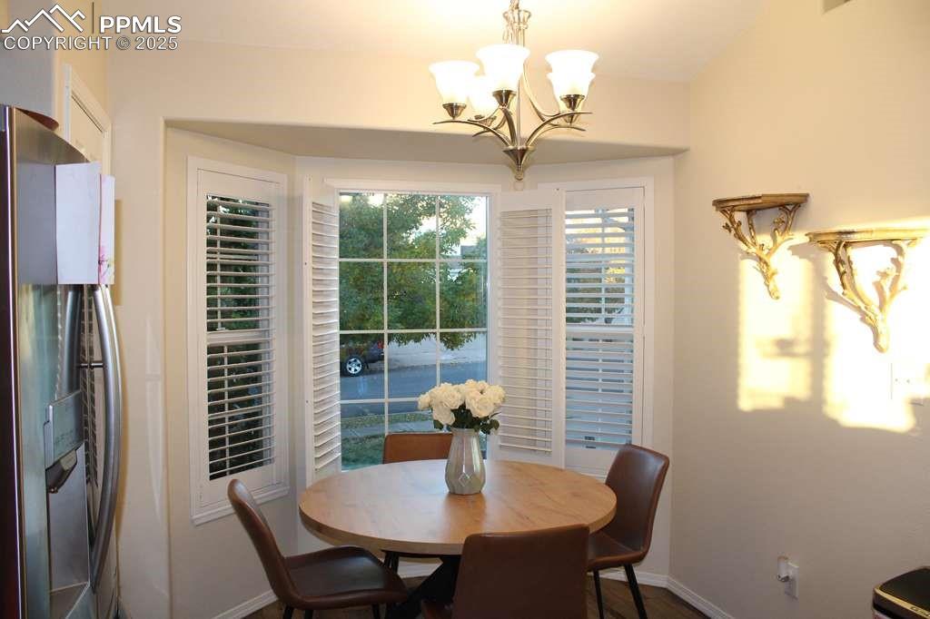 Dining area with a chandelier and dark wood-style flooring