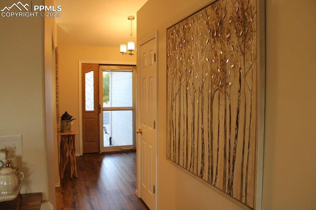 Entryway with dark wood finished floors and a chandelier