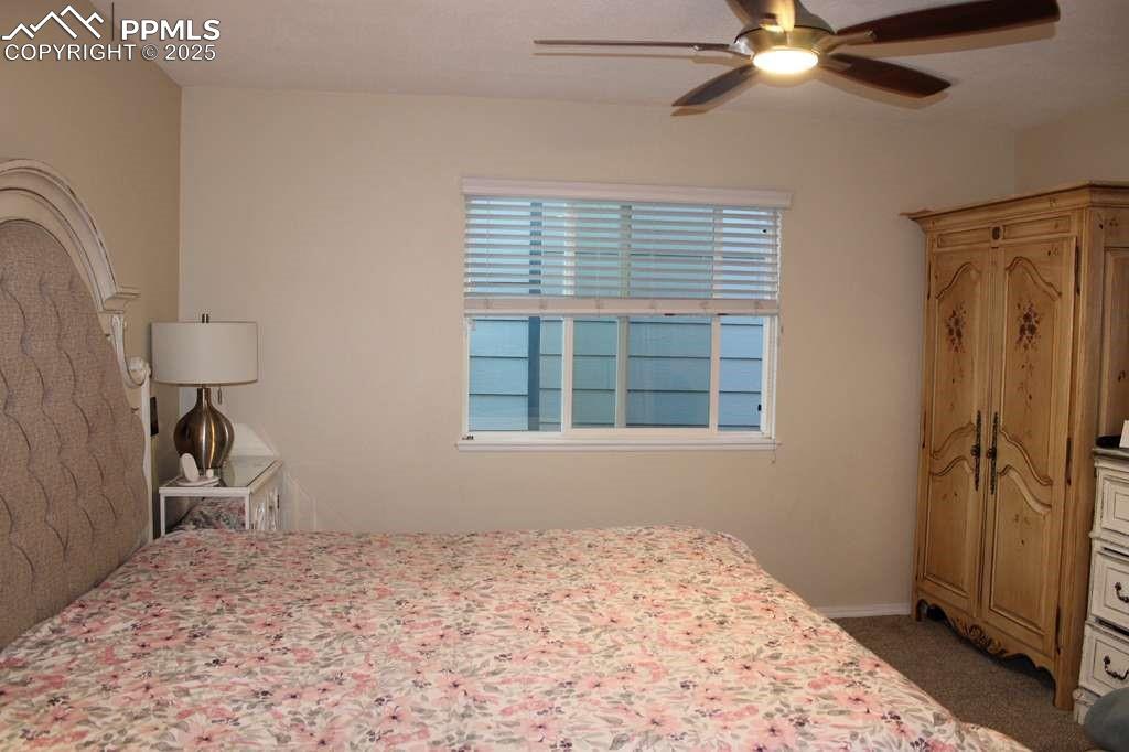 Bedroom with a ceiling fan and dark carpet