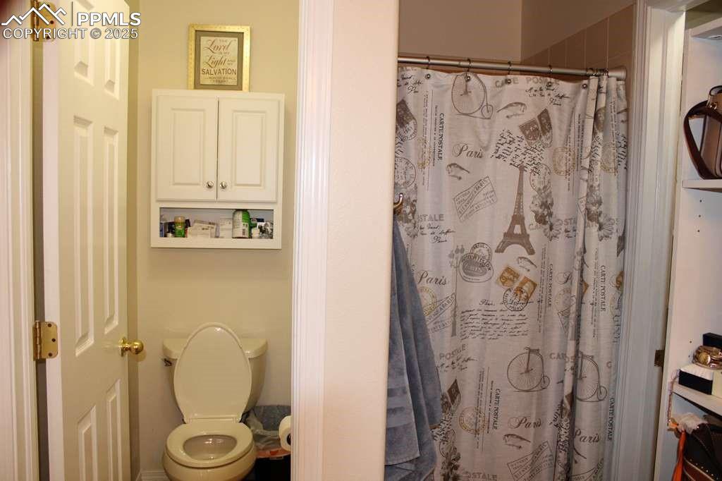Bathroom with toilet and curtained shower