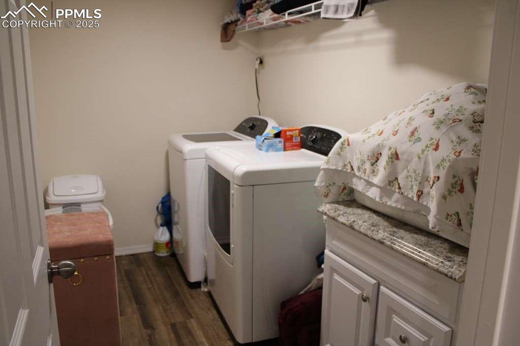 Washroom with dark wood-style flooring and washer and clothes dryer